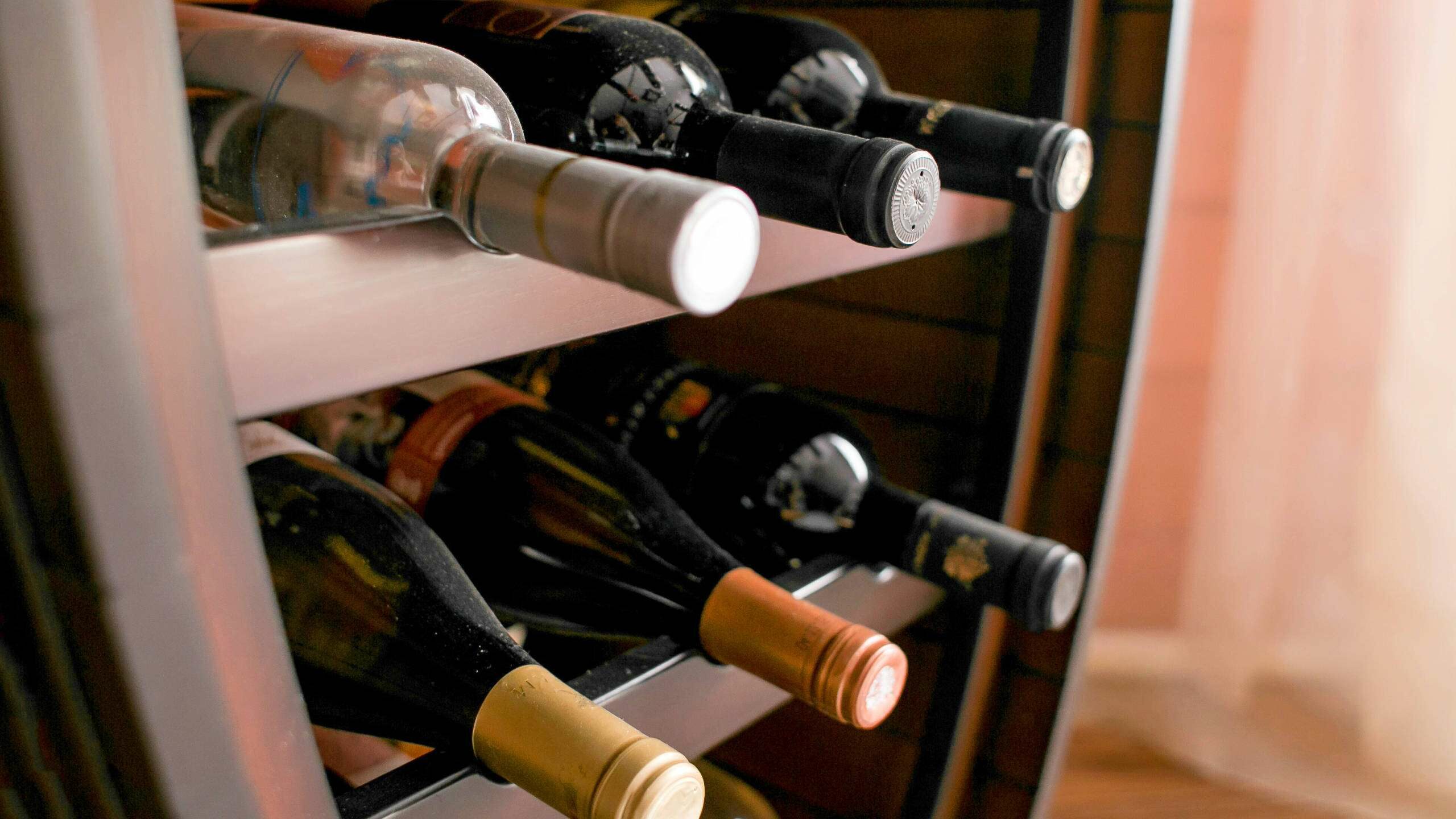 Bottles of white and red wine on a wooden shelf in private winery cabinet room interior