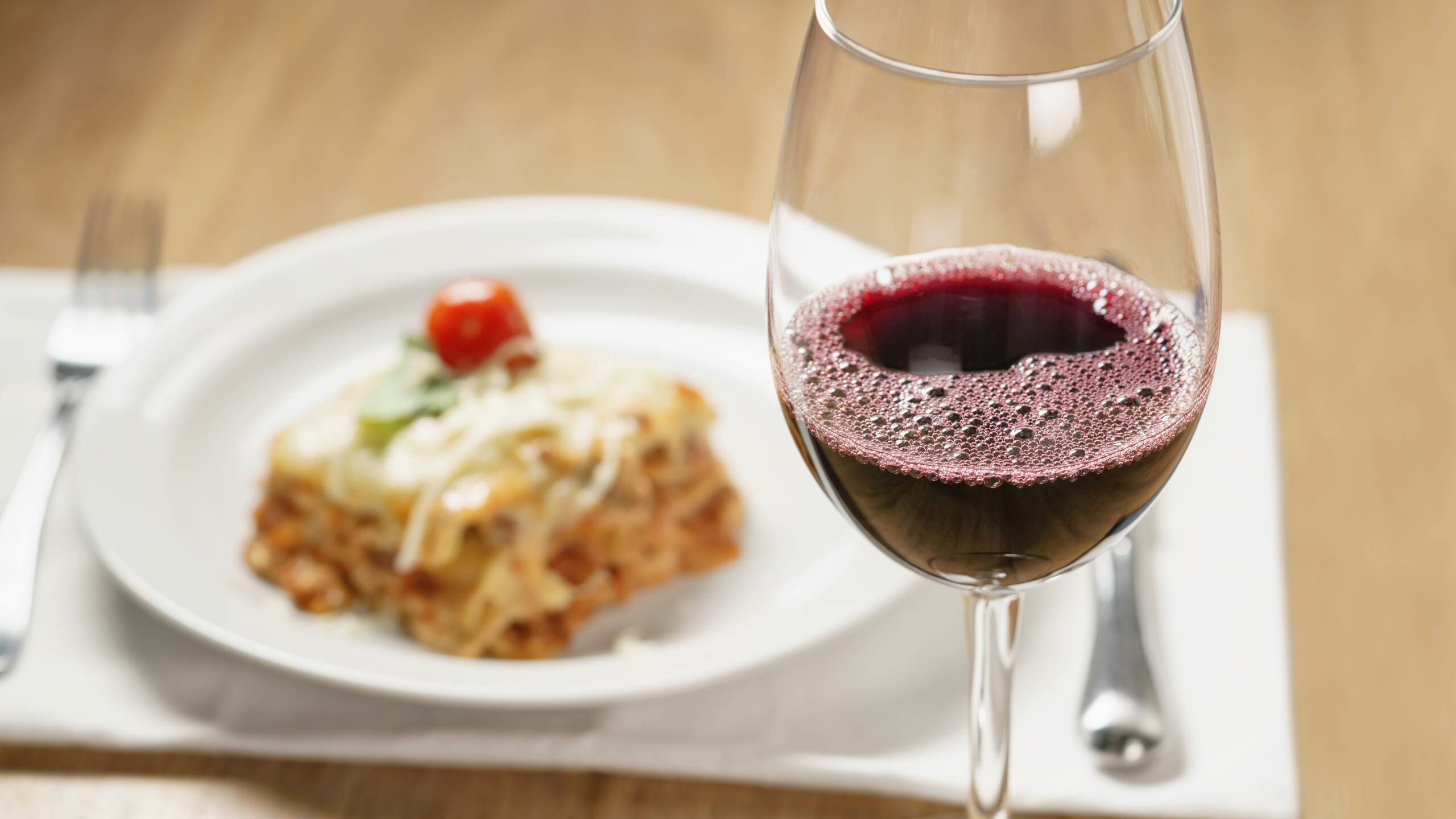 homemade lasagna with red wine on wood table