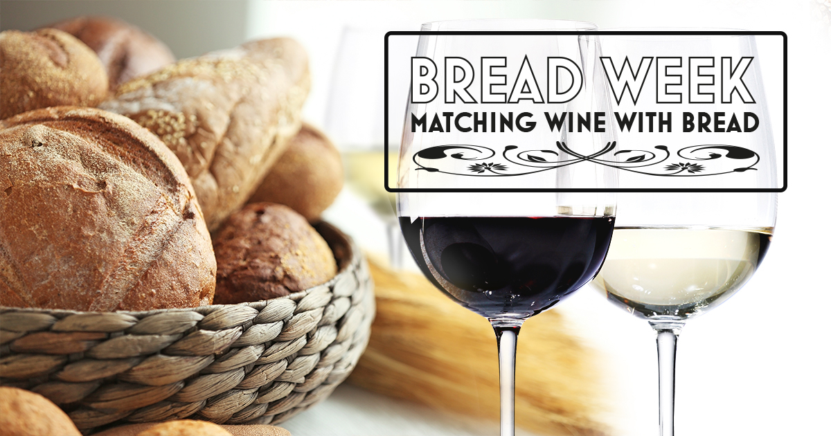 Glass of red wine next to basket of bread