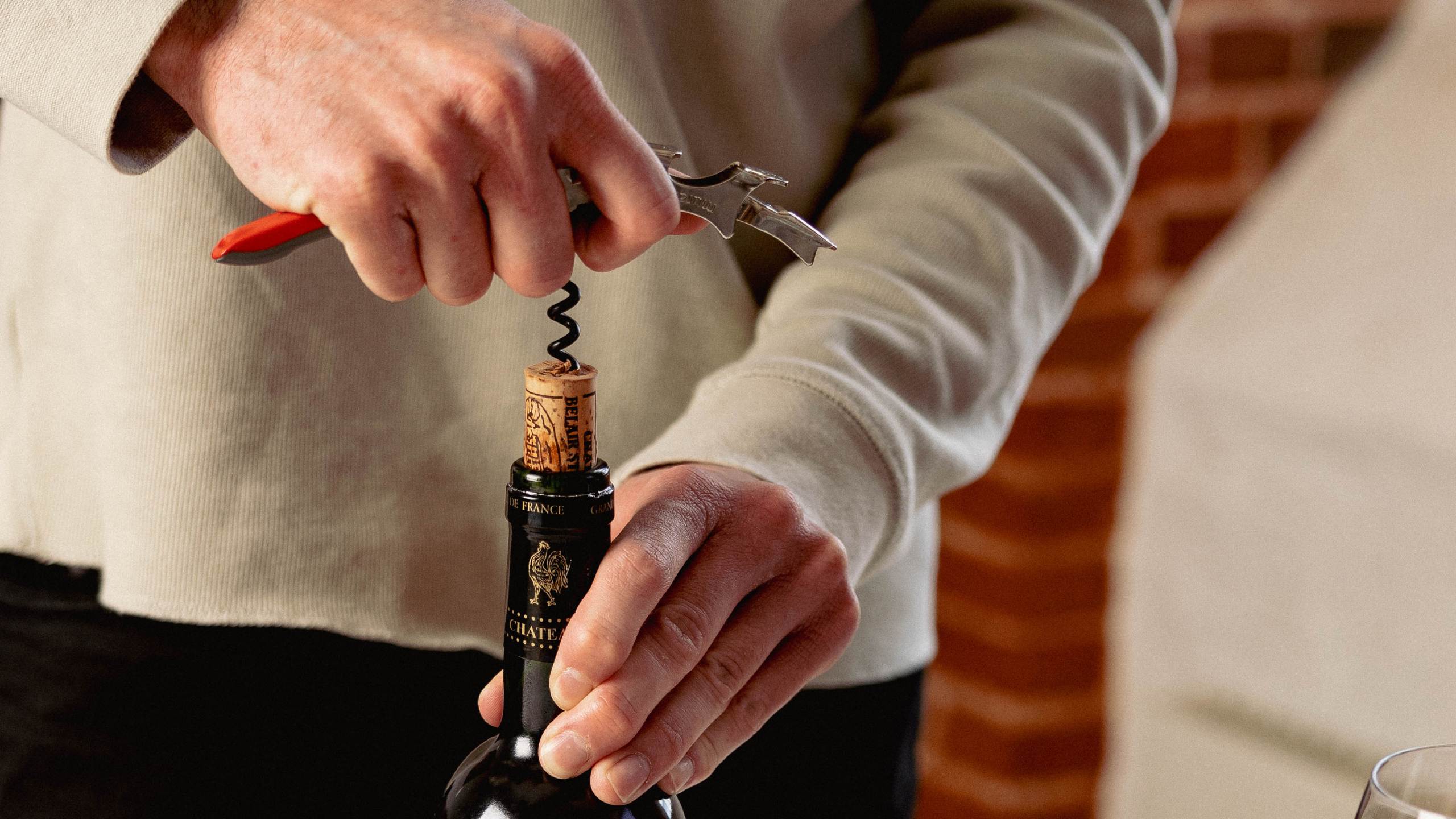 Man opening wine with a corkscrew to represent cork vs screw cap