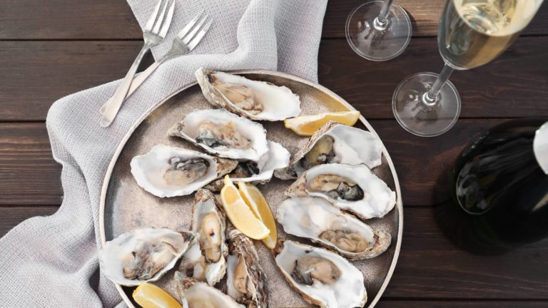 Fresh oysters with cut juicy lemon served on table, flat lay