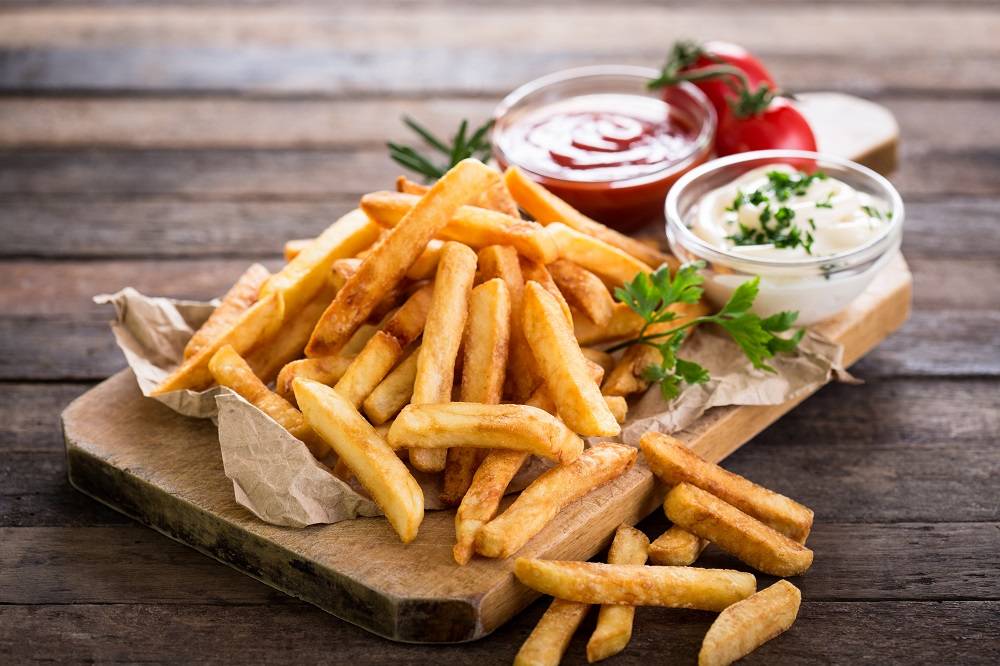 French fries on a wooden board with dips