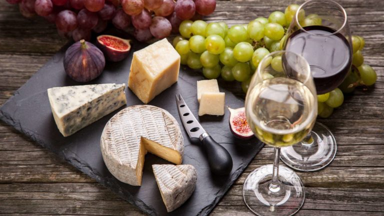 Cheese board with cheese and grapes with glasses of white wine and red wine