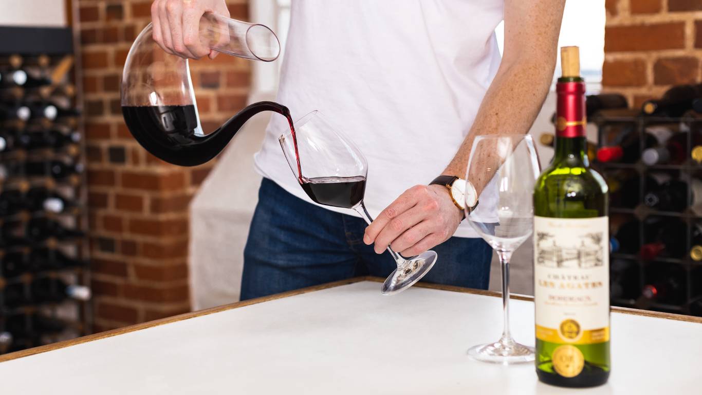 Man pouring red wine out of a wine decanter into a wine glass