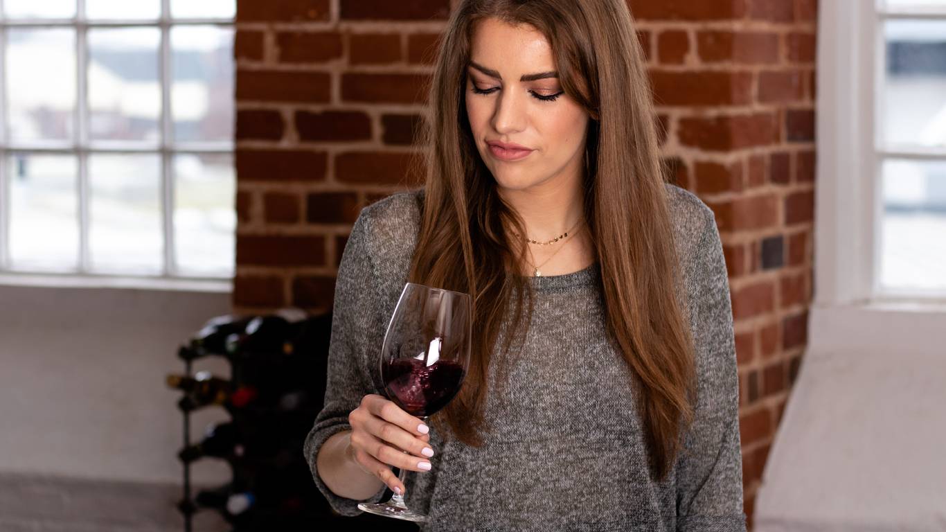 Woman about to smell red wine in tasting glass