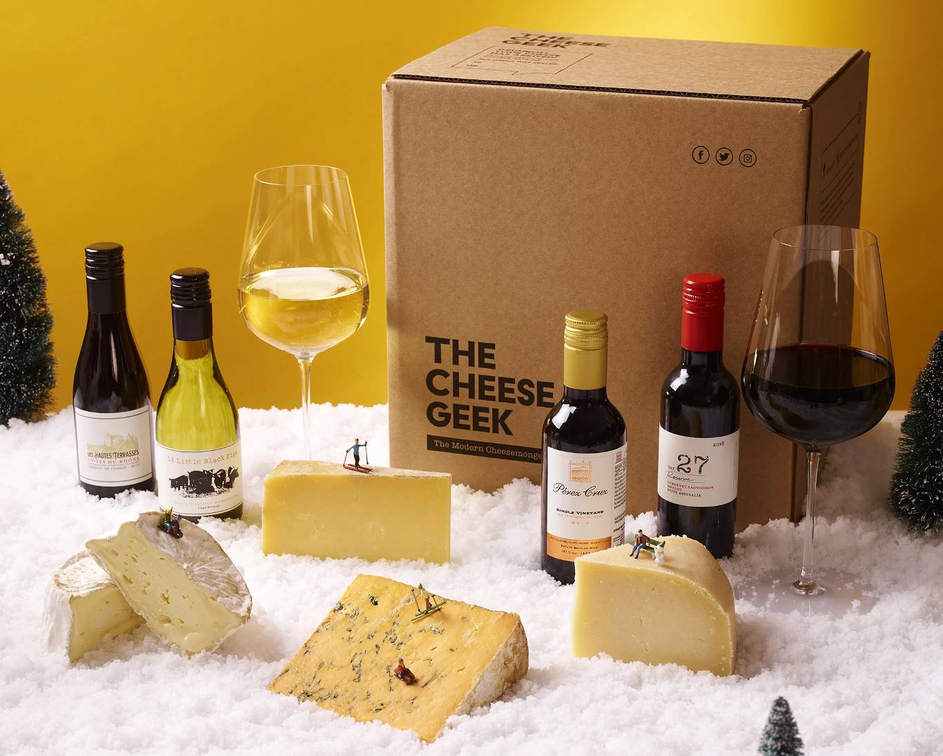 Wine bottles and various cheeses with cheese geek box