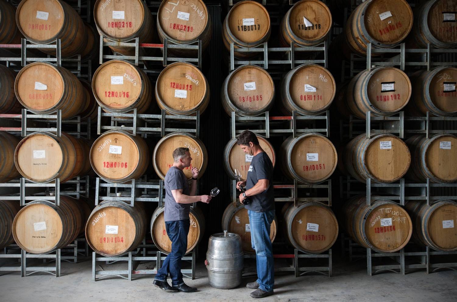Andrew Baker and Steve Grimley talking in front of barrels of wine