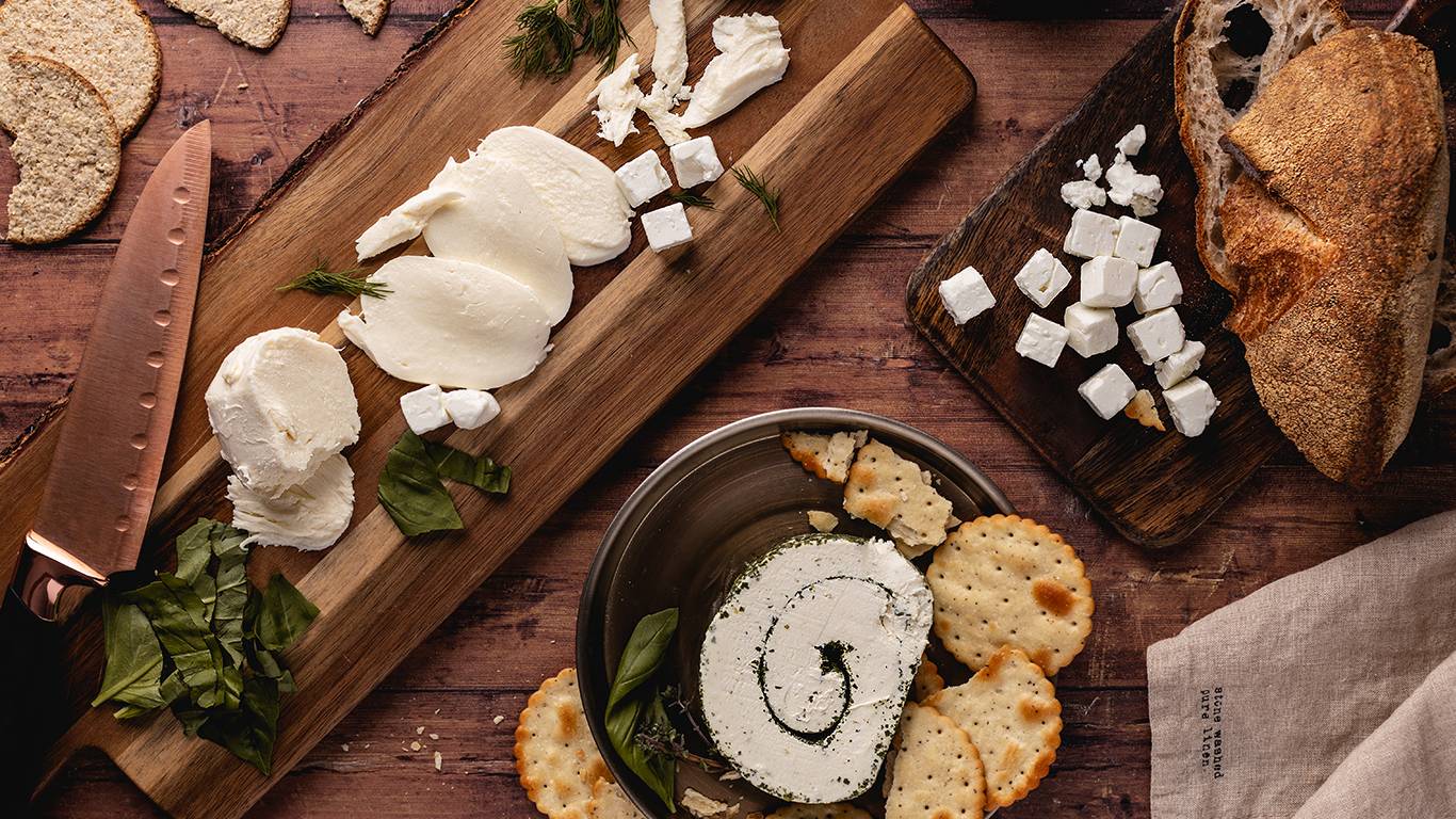 Various fresh cheeses on a wooden board
