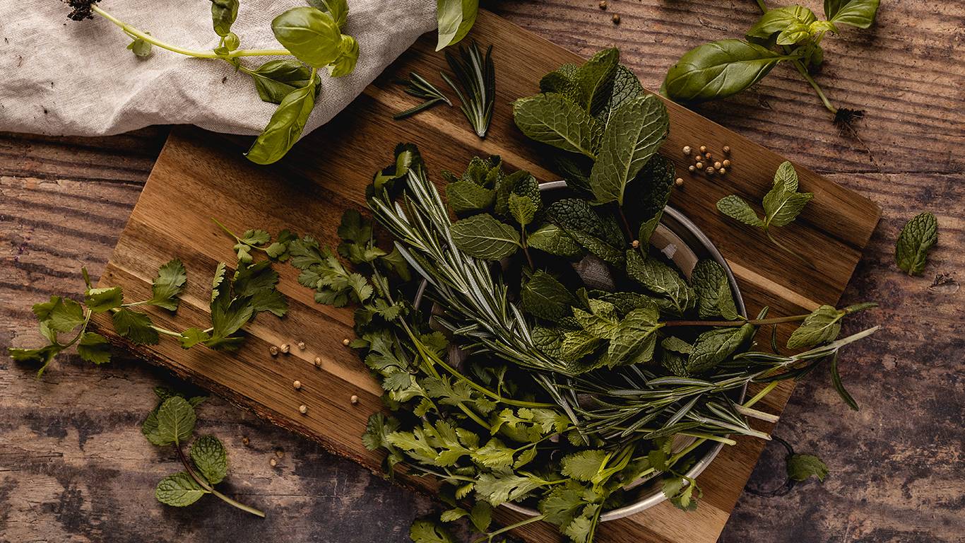 Various fresh green herbs on a wooden board