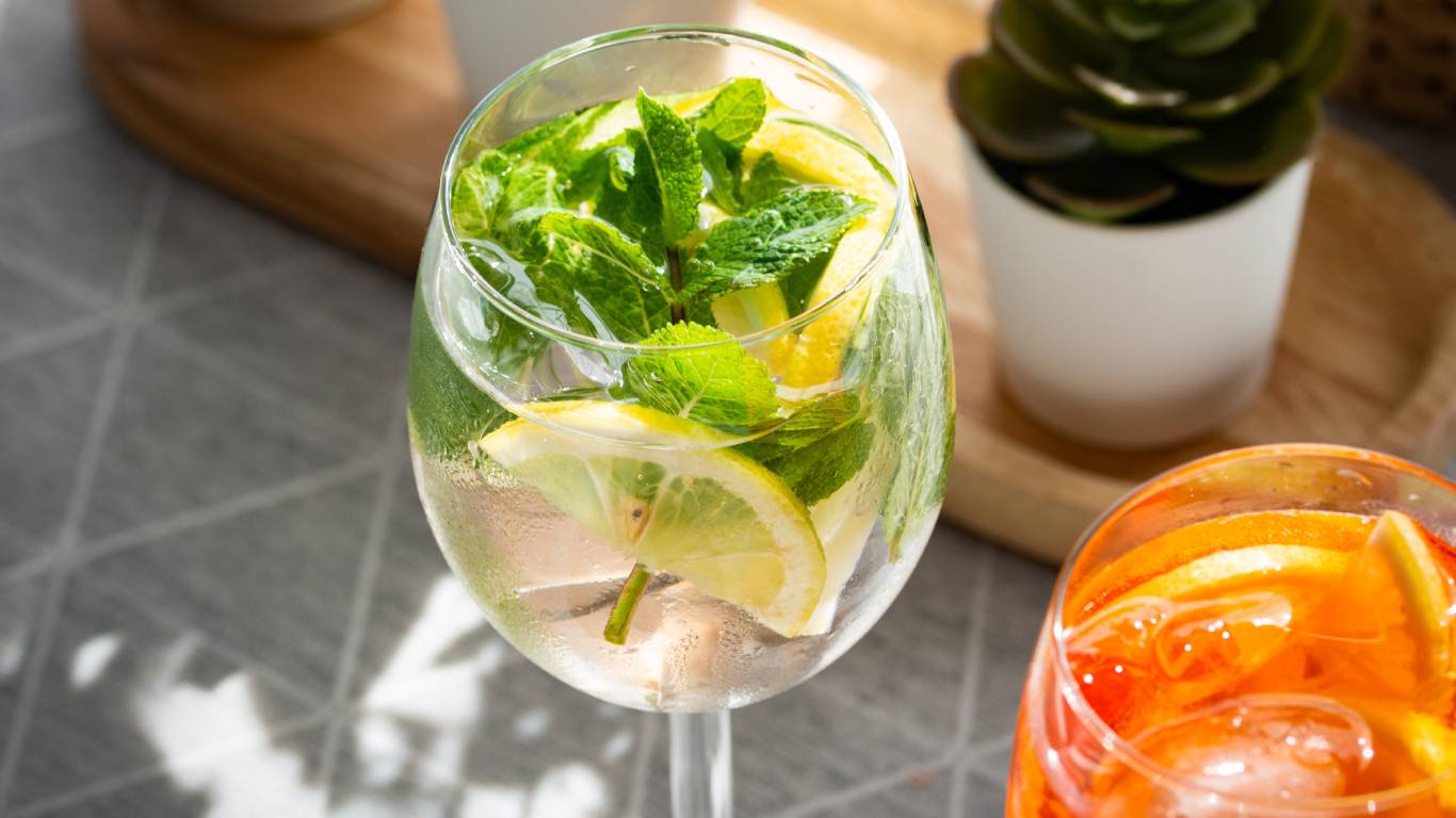A gin and tonic cocktail with lots of mint and lemon
