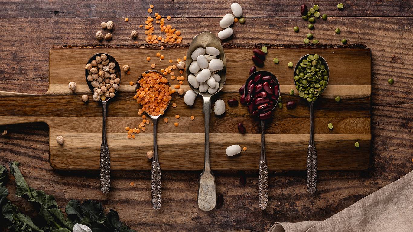 Various legumes on a wooden board including kidney beans and lentils
