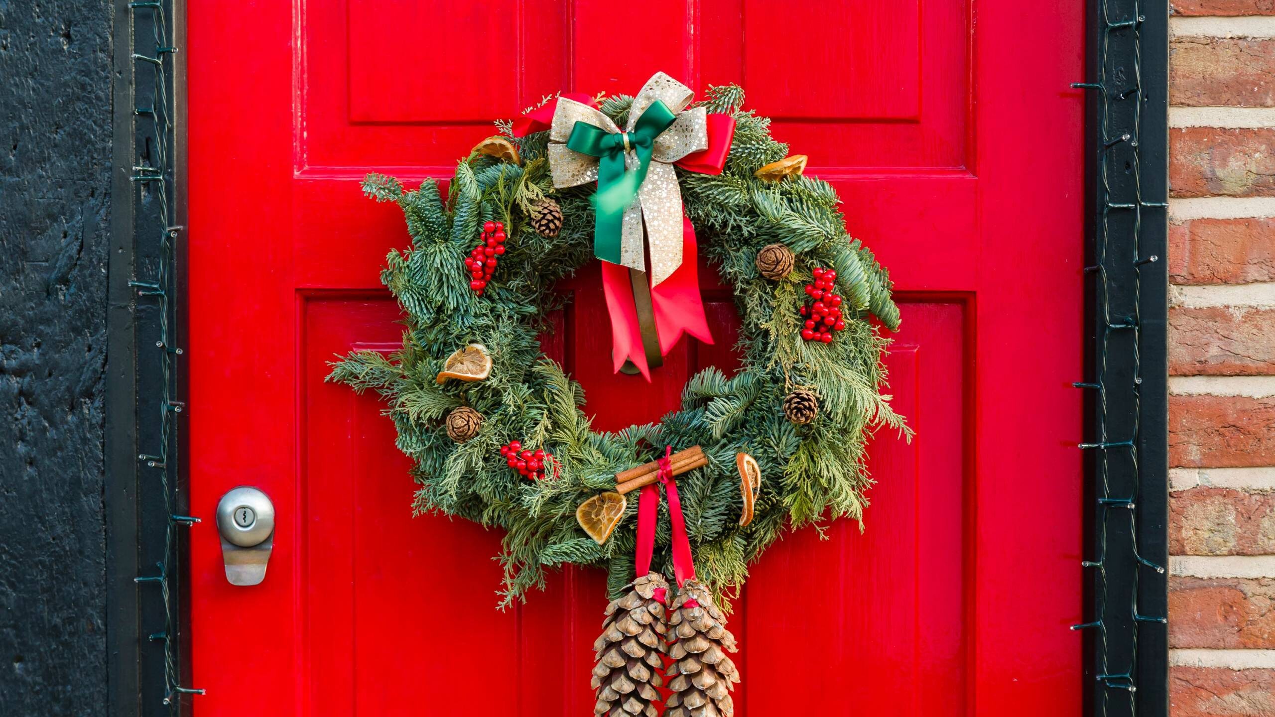 Red front door in England with Christmas wreath hanging on it
