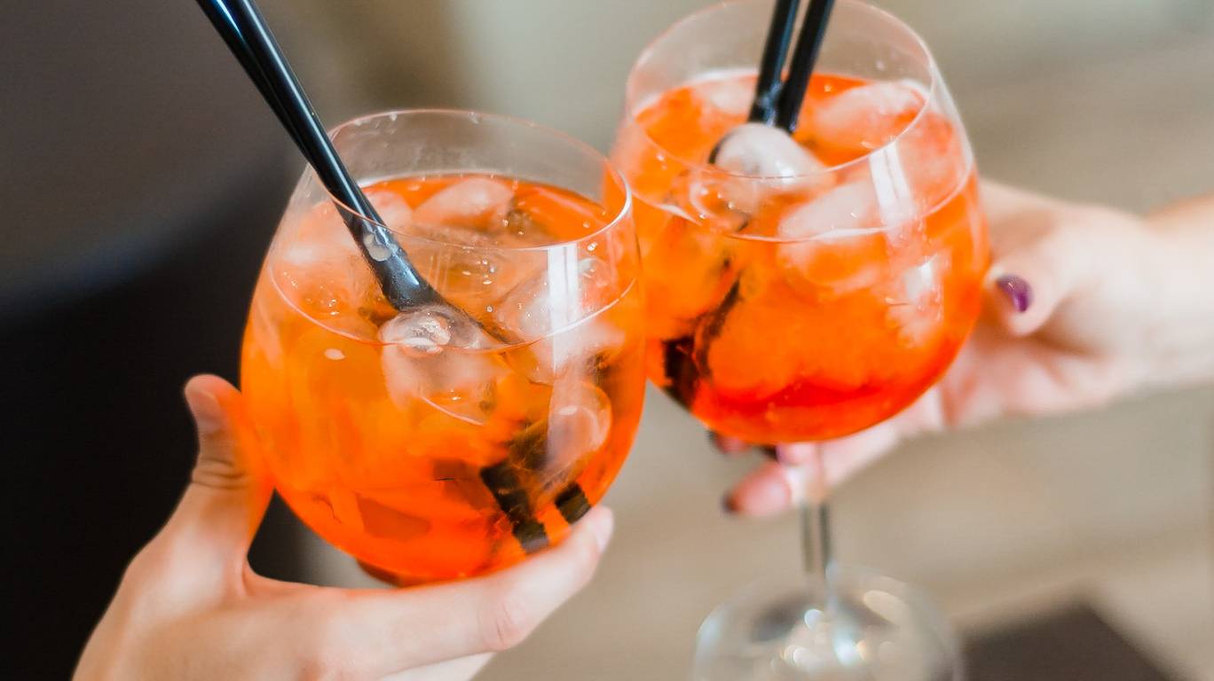 Two people holding aperol cocktails