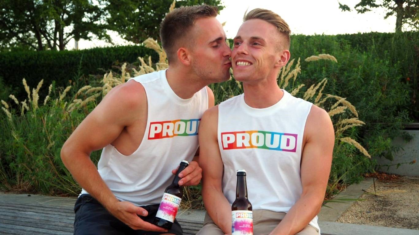 Ethan Spibey and his fiance holding bottles of PROUD beer