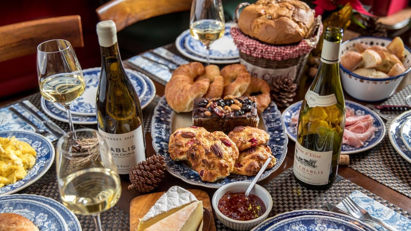 Two bottles of Chablis on a table surrounded by food