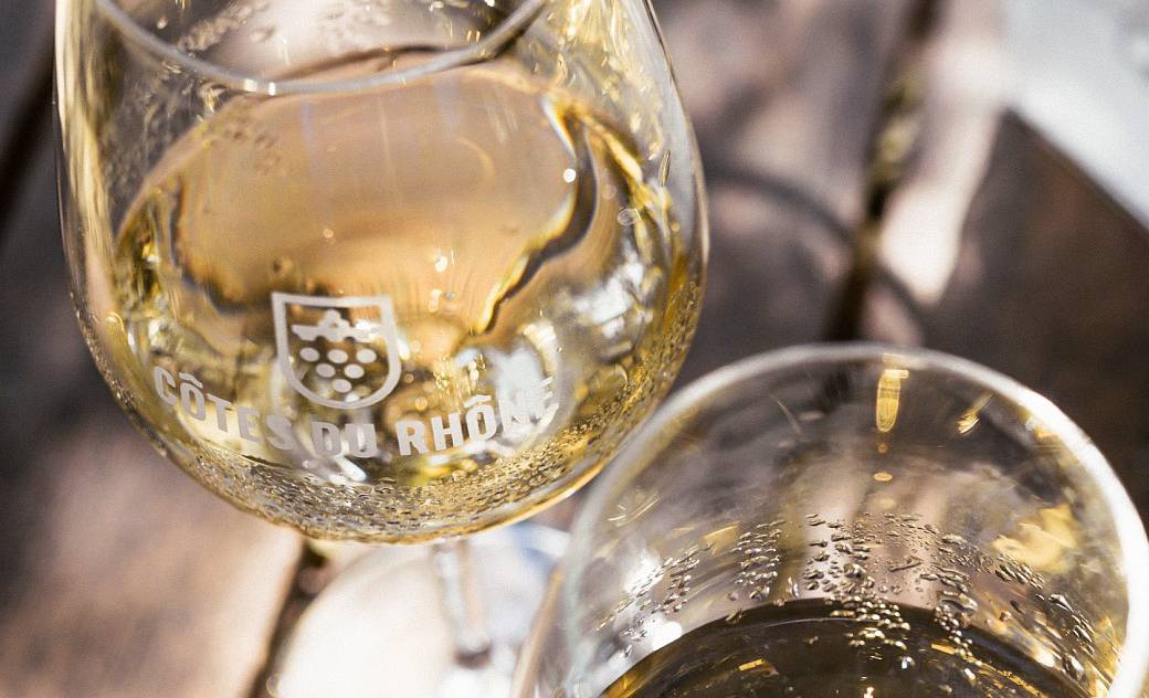 Close up of glasses of chilled white wine in Cotes du Rhone branded glasses, copyright Camille Meffre