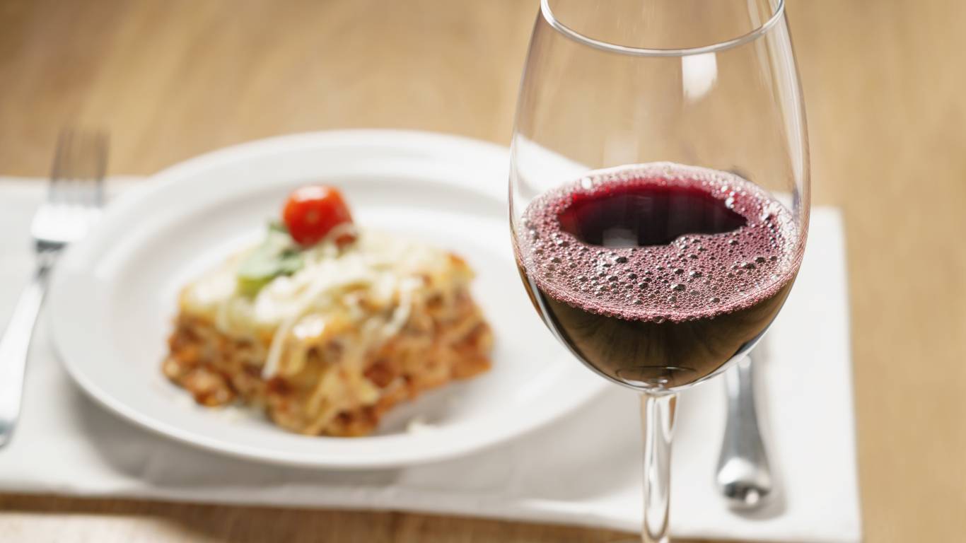 homemade lasagna with red wine on wood table, shallow focus