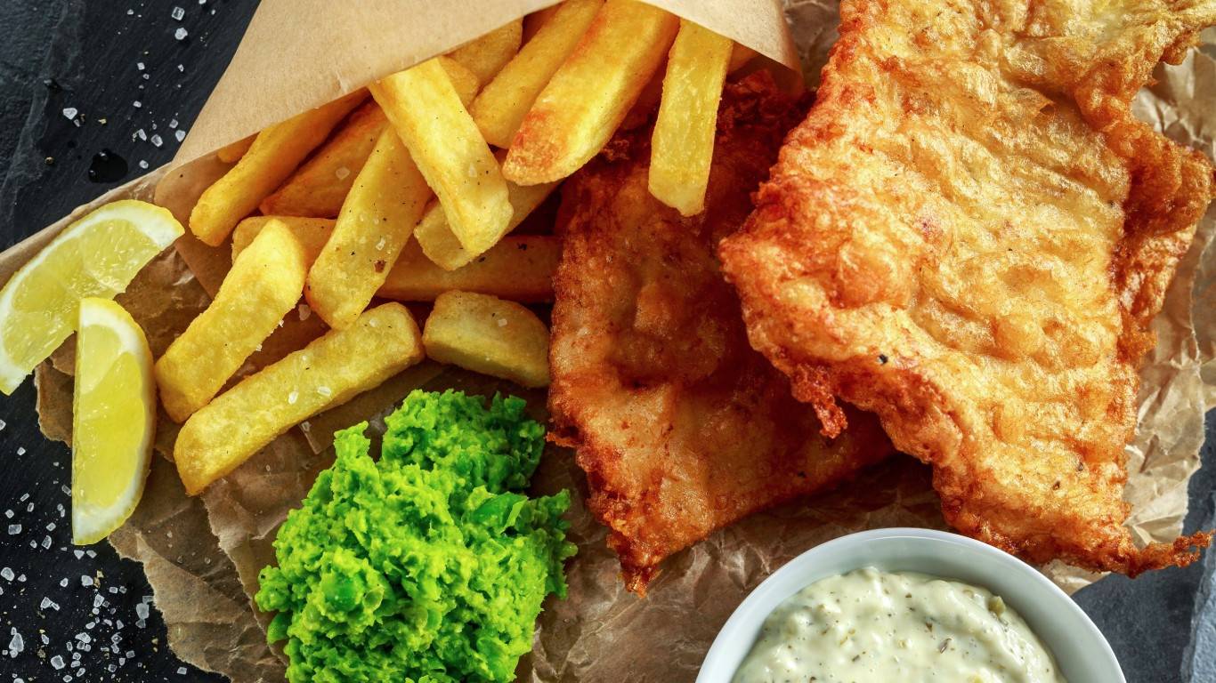 Fish and chips with sliced lemon, a pot of tartar sauce and dollop of mushy peas