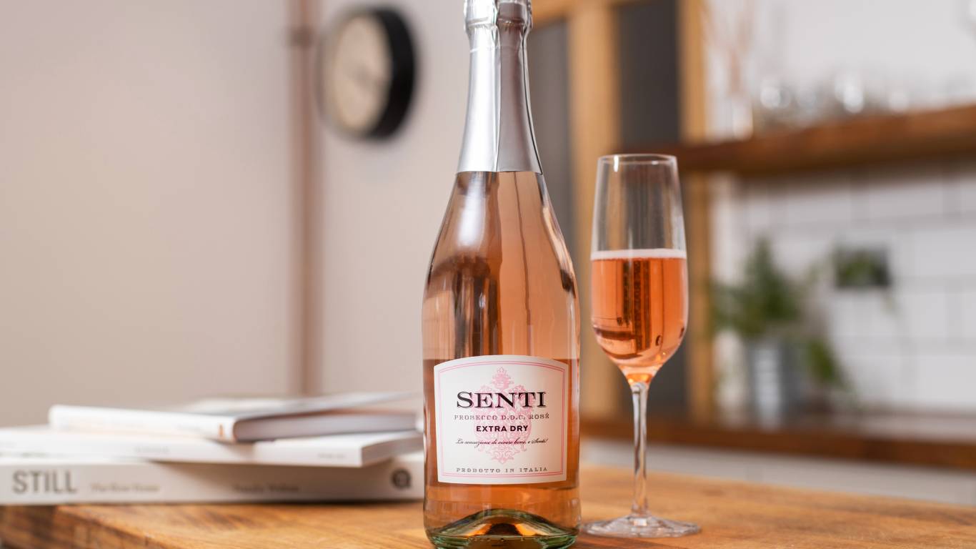 Bottle of Senti Prosecco Rose Extra Dry on a kitchen worktop next to a flute of pink Prosecco