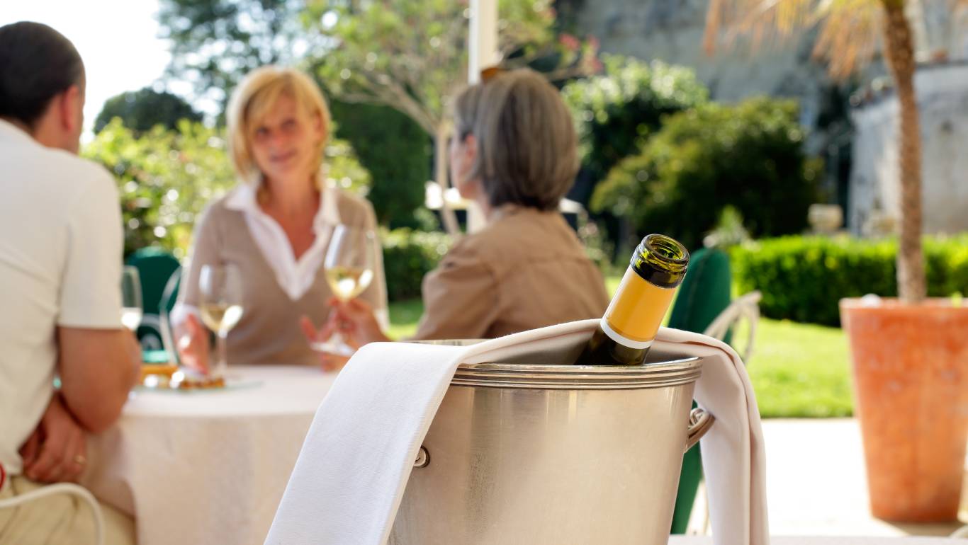 Bottle of white wine from Loire Valley being chilled in an ice bucket by people having dinner outside