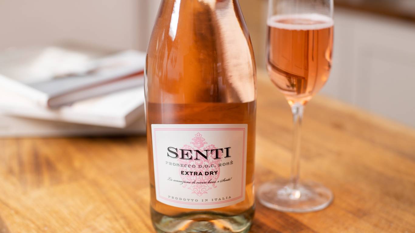 Close up of Senti Prosecco Rose Extra Dry on a kitchen worktop next to a flute of pink Prosecco