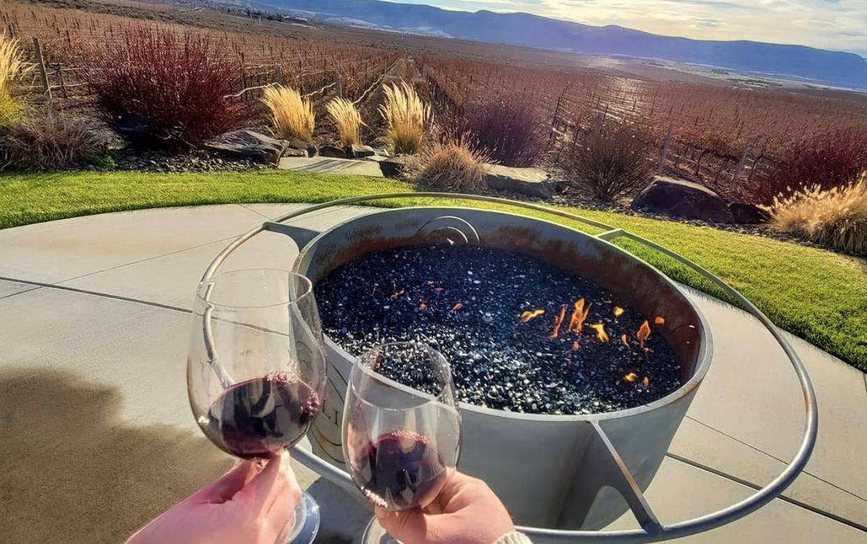 Couple drinking red wine by firepit overlooking Washington landscape