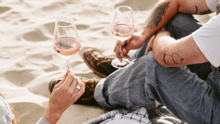 Two people drinking glasses of rose wine in the beach with a picnic in Bordeaux