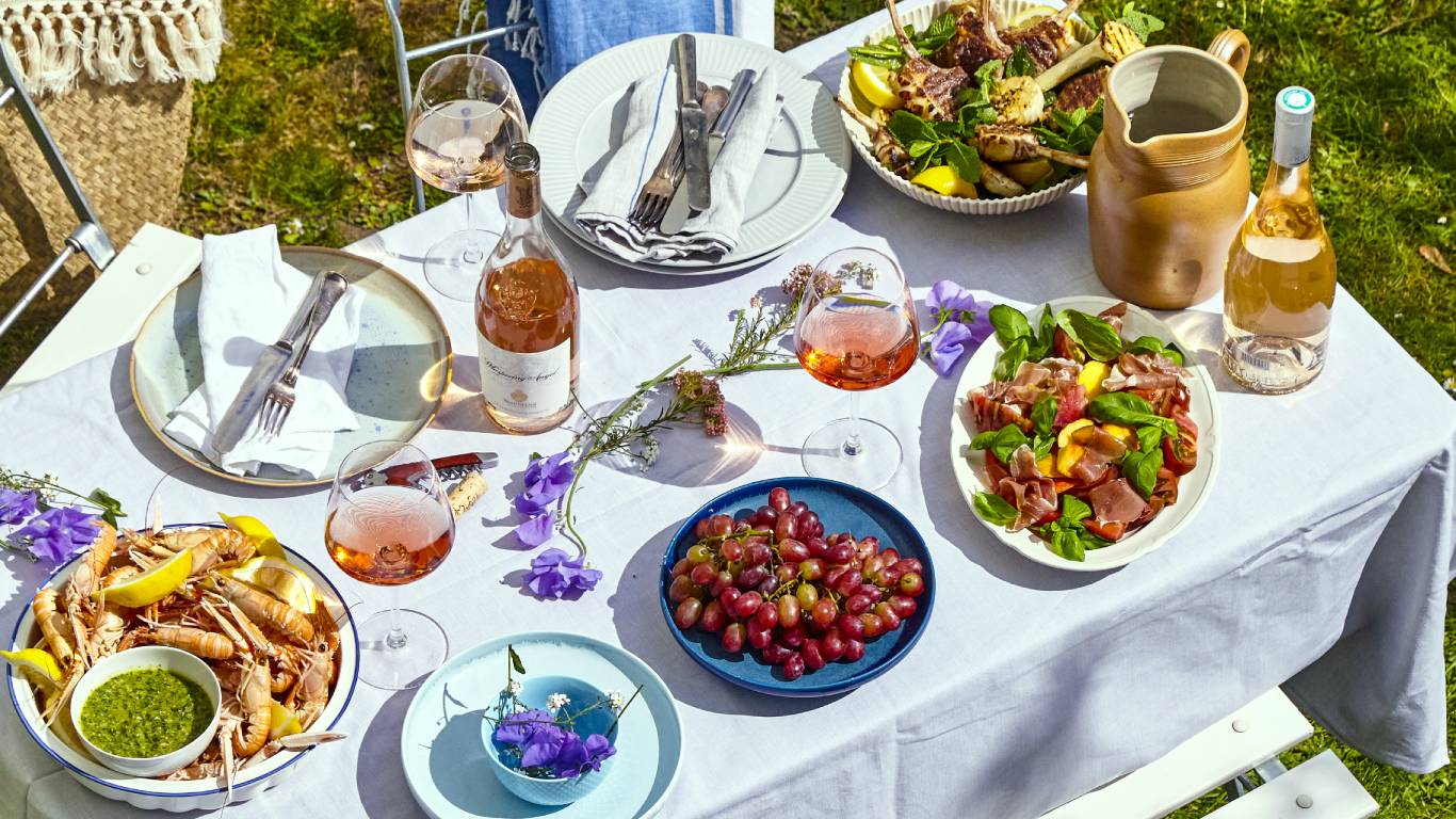 Glasses of Provence rose on a table outside with plates of food