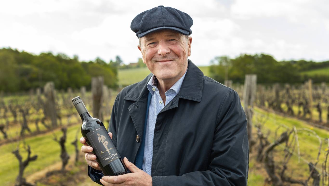 Phil Tufnell holding a bottle of Tuffers' Tipple Margaret River Shiraz 2019 in New Hall vineyard, Essex