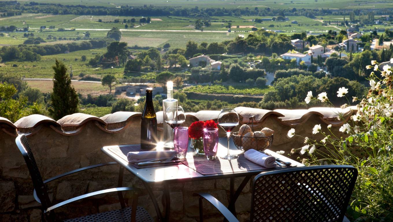 Glasses of wine on a table on a balcony overlooking a vineyard in Rhone Valley