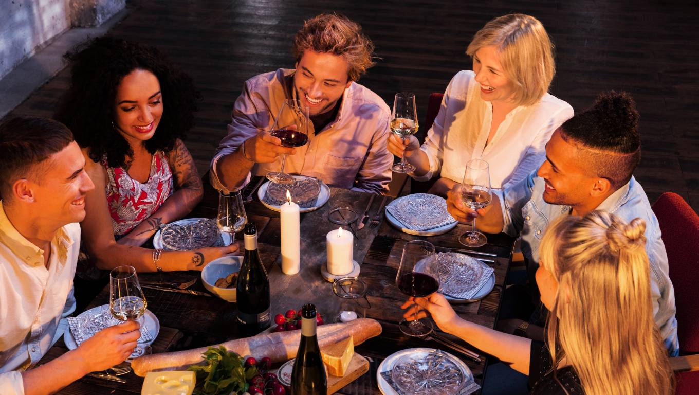 group of friends around a table outside holding glasses of wine