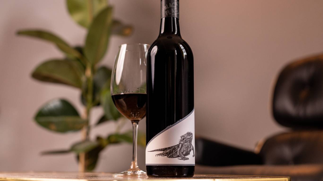 Black Flag Winemakers Langhorne Creek Adelaide Hills Shiraz 2018 by a glass of wine on a coffee table by a chair