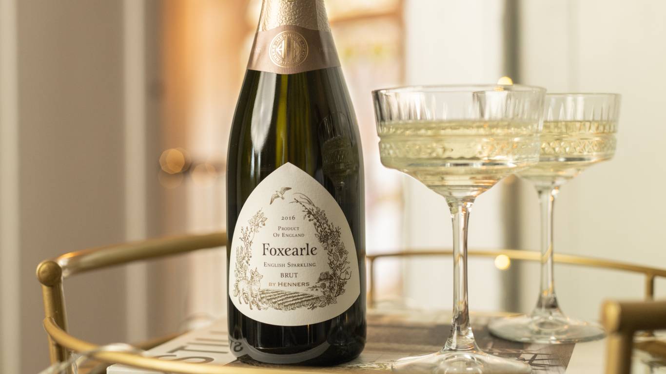 Bottle of Henners Foxearle English Sparkling Brut 2016 on a gold drinks trolley with a glass of sparkling wine