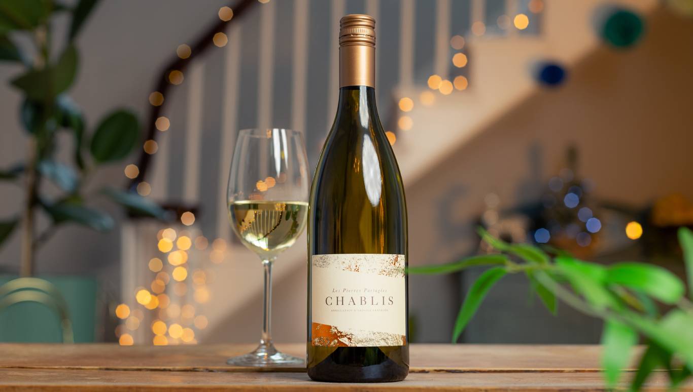 Les Pierres Partagees Chablis with a glass of white wine in front of a festive staircase