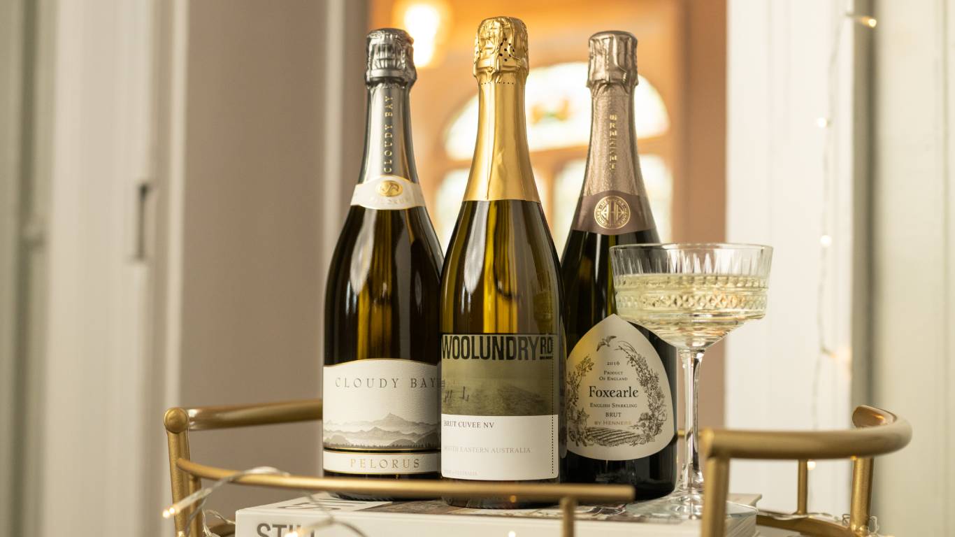 Three bottles of sparkling wine alternatives to Champagne on a gold drinks trolley