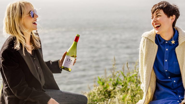 Two friends enjoying a bottle of Vin De France wine by the seaside