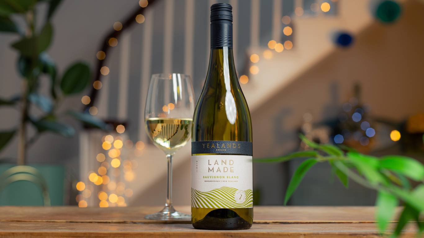 Yealands Estate Land Made Sauvignon Blanc with a glass of white wine in front of a festive staircase
