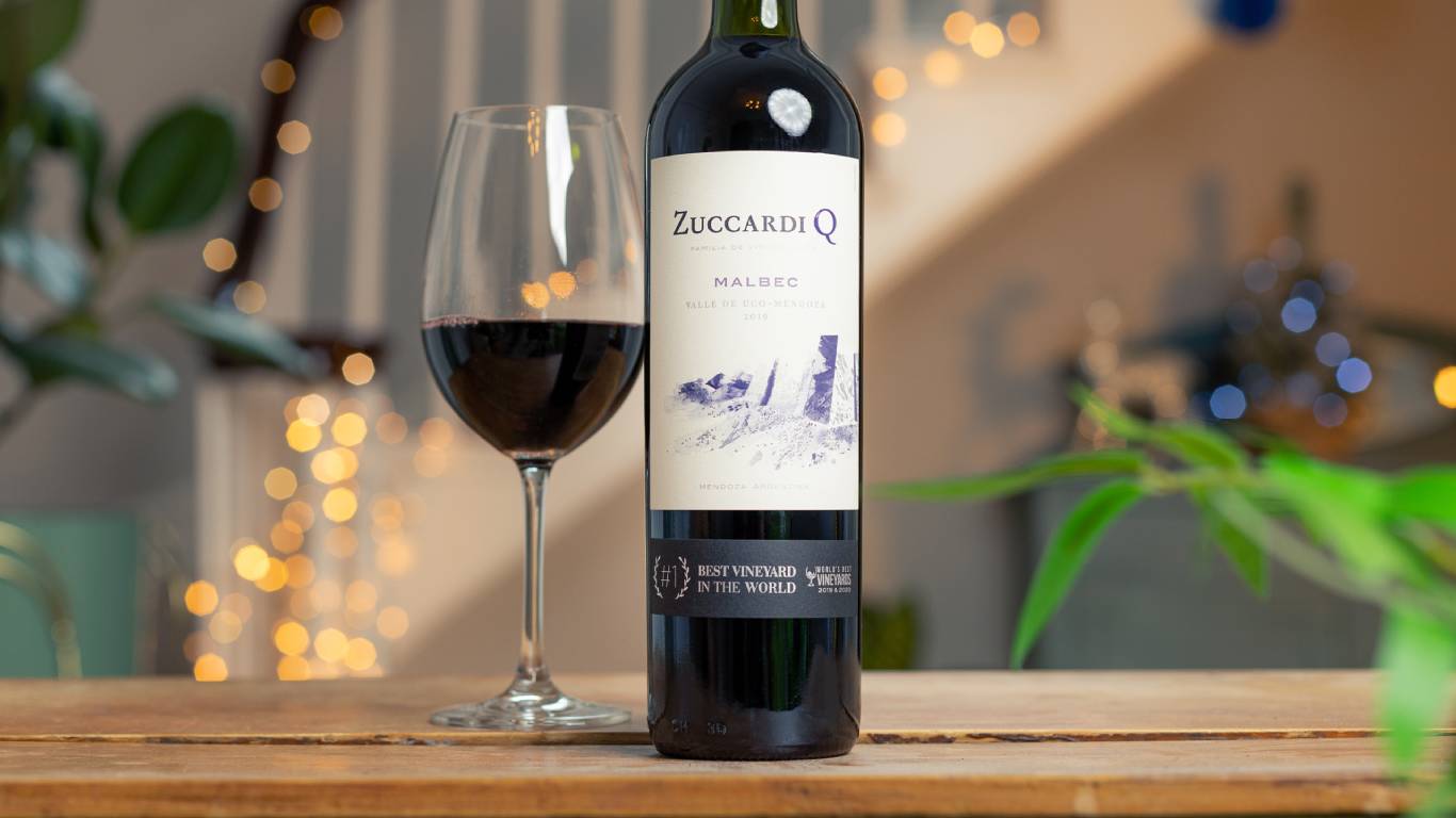 Zuccardi Q Malbec beside a glass of red wine in front of a festive staircase