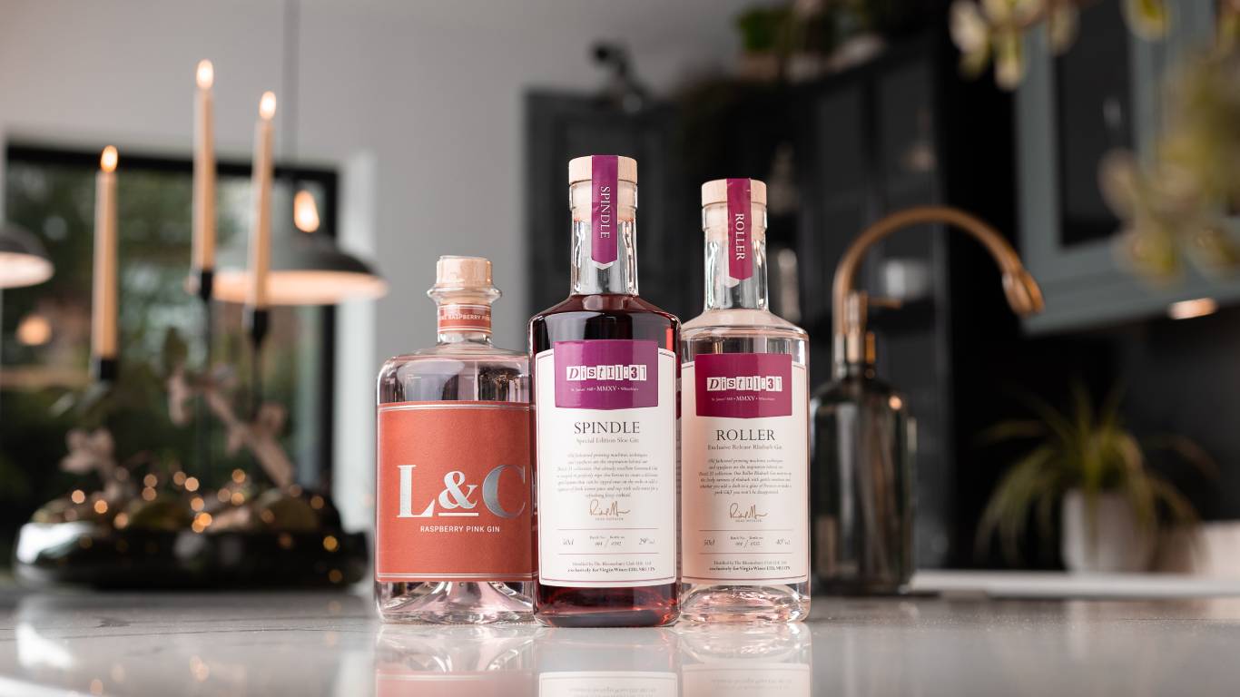 L&C Pink Raspberry Gin with a sloe gin and a rhubarb pink gin on a festive kitchen worktop
