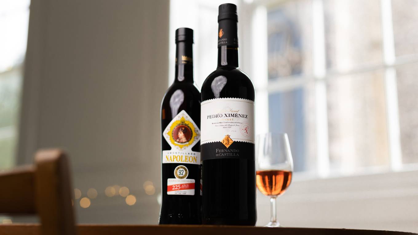 two bottles of sherry on table in front of window