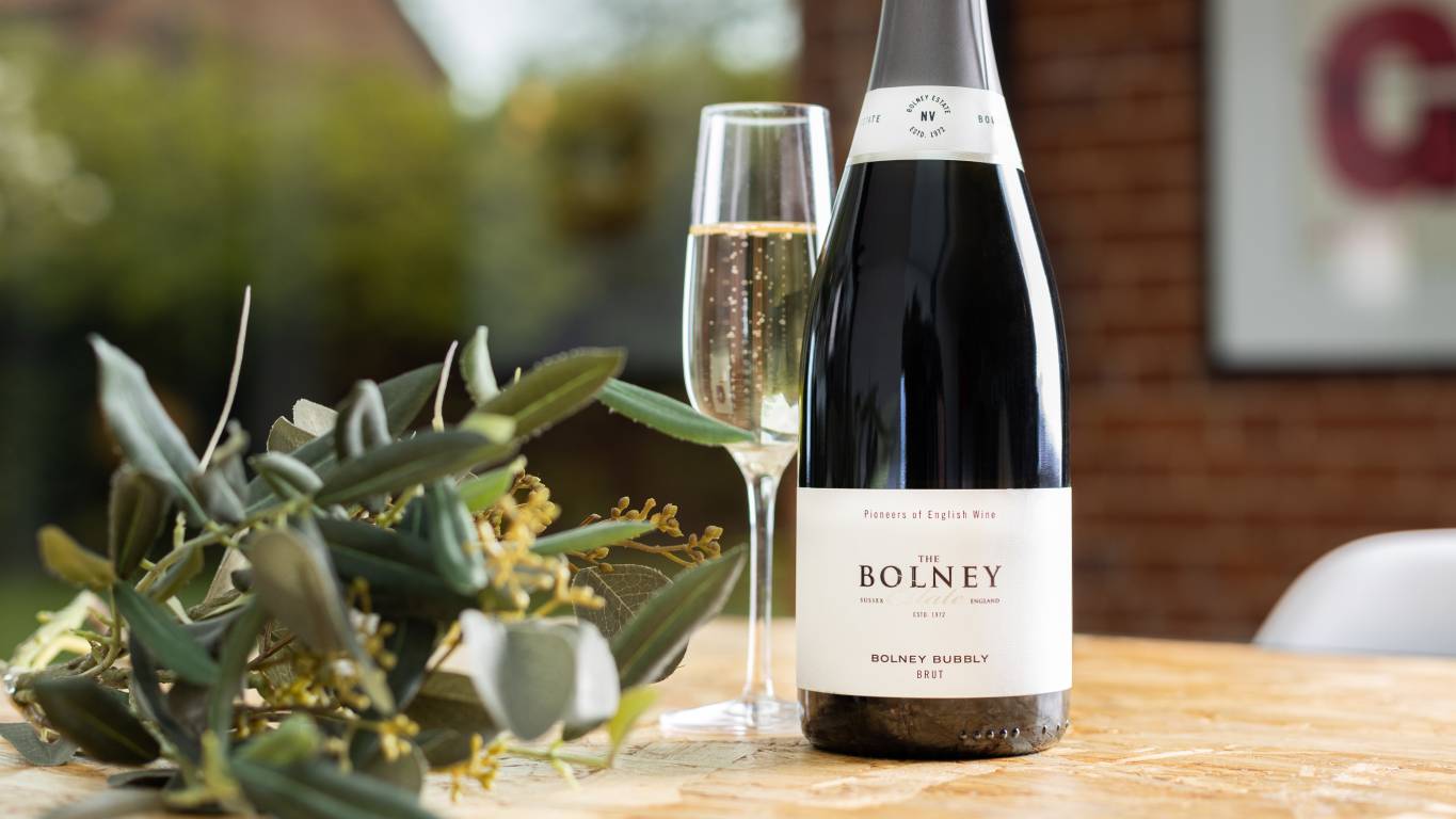 Bottle of The Bolney Estate Bolney Bubbly Brut on a dining table with flowers