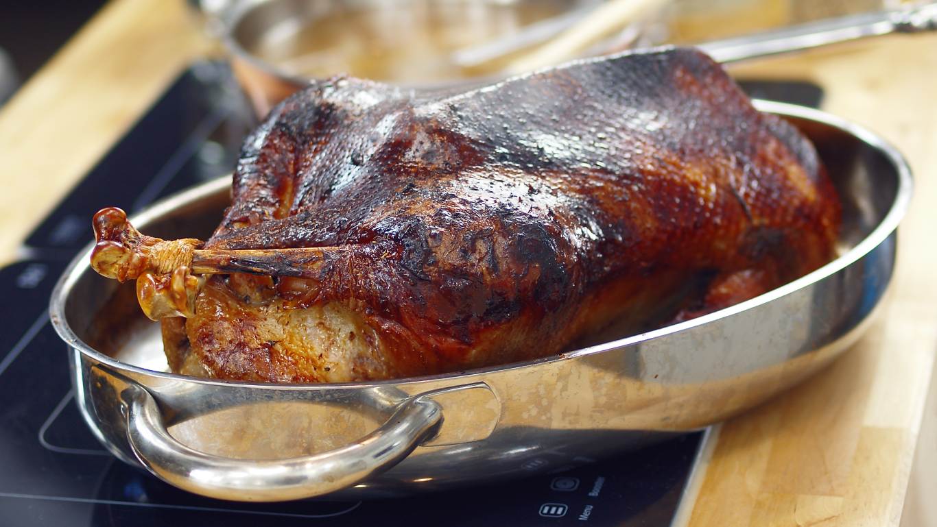 Roast goose in a metal tray on a kitchen worktop