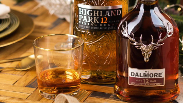 Bottle of Highland Park 18 Year Old Viking Pride Whisky and Dalmore 12 Year Old Single Malt Whisky on a decorated dining table with a whisky tumbler