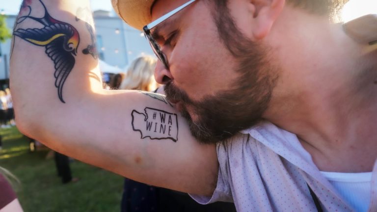 Man kissing a tattoo about Washington Wines on his arm