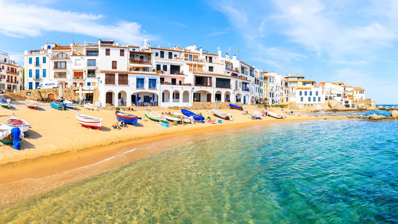 Panorama view of a beach in a scenic fishing village with white houses and sandy beach with clear blue water, Costa Brava, Catalonia, Spain