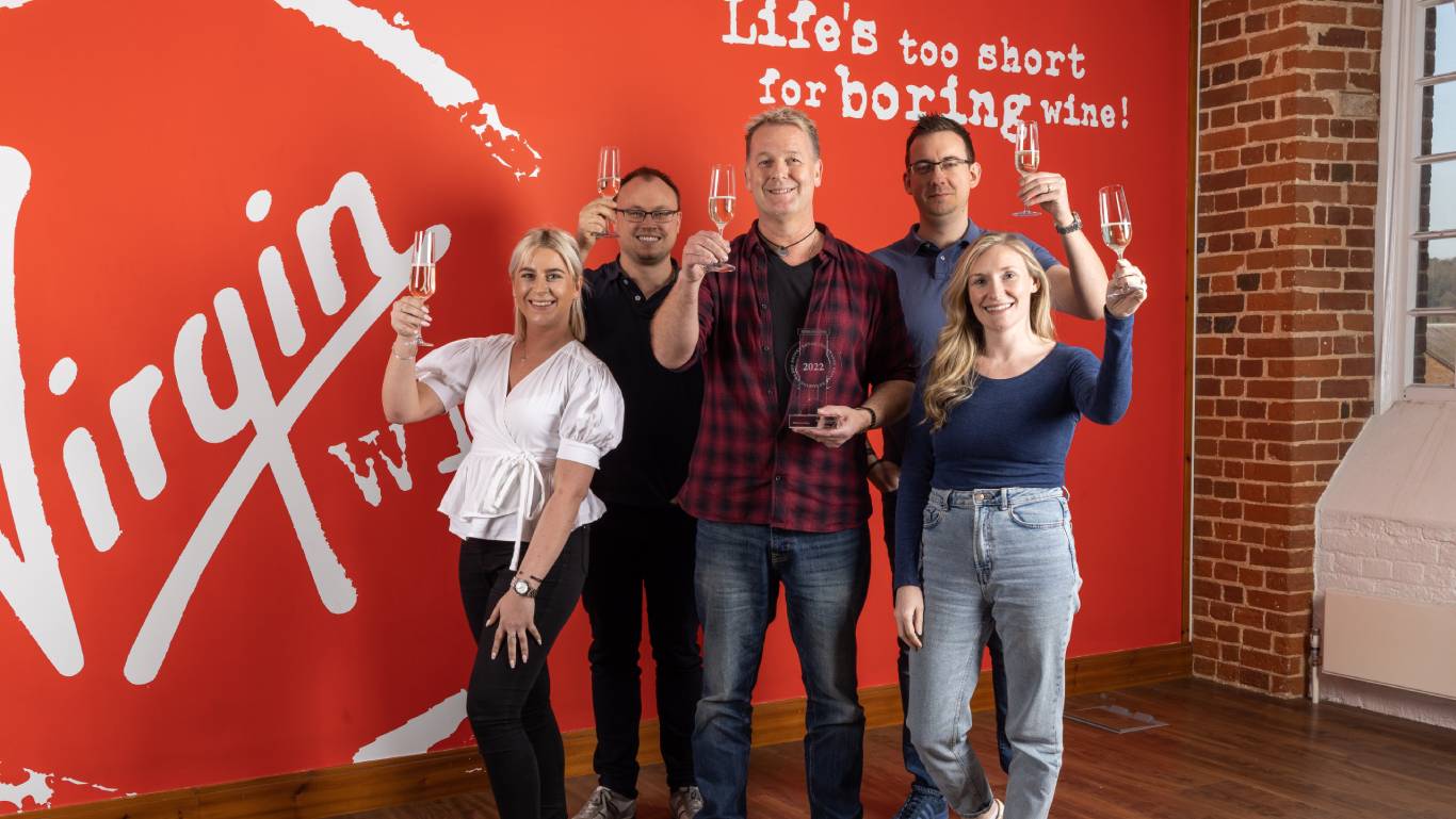 Group of Virgin Wines staff in their office holding glasses of wine, with Virgin Wines CEO Jay Wright in the middle holding the Specialist Online Drinks Retailer of the Year award