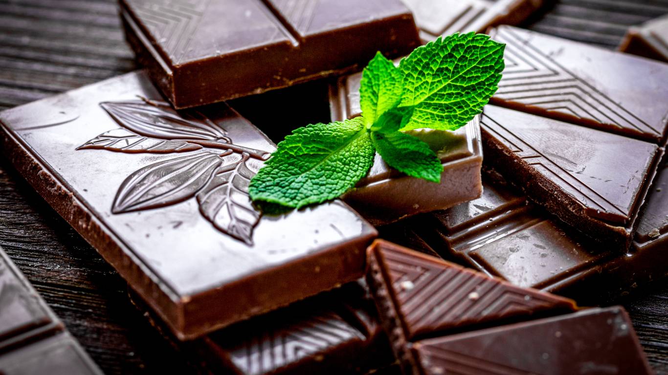 Chunks of dark chocolate and mint on a dark wooden surface