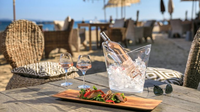Bottle of Vin De Provence Rosé in ice bucket on table by beach with platter of food