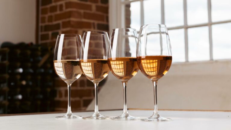 Four glasses of rose wine lined up on a table showing different types of rose wine