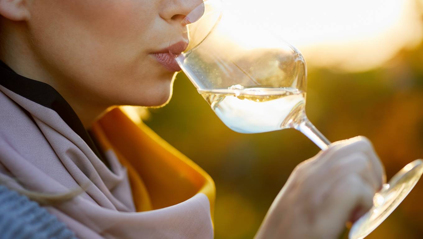 A lady drinking a glass of wine in front of sunset